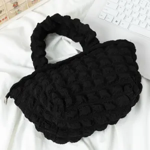 Primer plano de un bolso negro con textura de burbujas en un escritorio blanco limpio