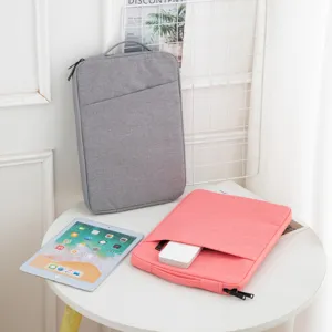 Graue und rosa Laptop-Hüllen mit iPad auf einem weißen Tisch im Lifestyle-Stil