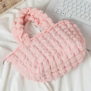 Vista detallada de un bolso rosa con textura de burbujas sobre una tela blanca suave