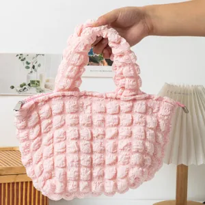 Vista detallada que muestra la textura de burbujas plisadas rosas de este bolso de mano