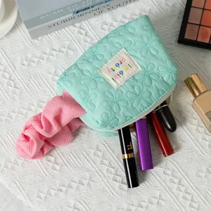 Close-up of mint green quilted makeup bag showing floral texture and lipstick storage