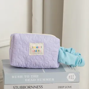 Close-up of light purple quilted makeup bag with floral embroidery and chic label