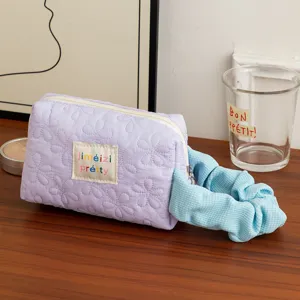 Detailed view of a quilted purple floral cosmetic bag featuring a blue scrunchie accessory