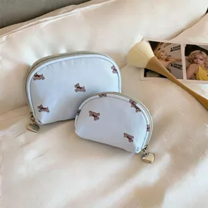 Detail of two light blue portable makeup bags with cute puppy pattern and heart zipper