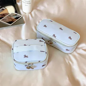 Detail view of two blue puppy print travel makeup bags with heart-shaped zipper pulls