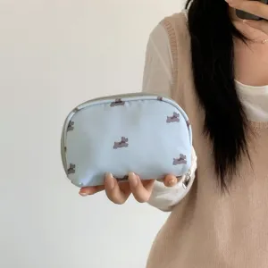 Detail view of portable light blue makeup bag with cute dog pattern held by hand