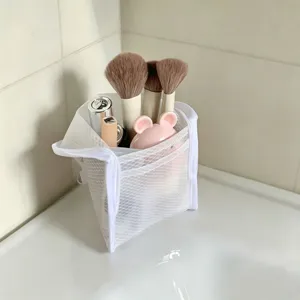 Close-up view of a white mesh travel organizer pouch filled with makeup brushes