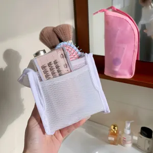 Close-up detail of a portable white mesh cosmetic bag holding makeup brushes and tools