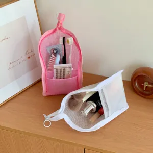 Close-up of portable pink and white mesh toiletry bags for travel on wooden table