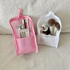 Close-up of pink and white mesh travel pouches storing toothbrushes and makeup brushes
