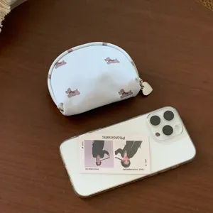 Compact light blue puppy print cosmetic bag next to a smartphone for size reference