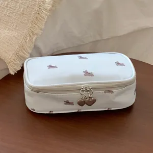 Close-up detail of a portable white dog pattern makeup bag with heart-shaped zipper pulls