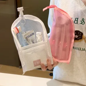 Detailed view of white and pink mesh storage bags holding travel toiletries and brushes.