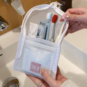 Detailed view of a white mesh travel toiletry bag holding brushes and toothpaste