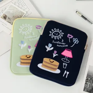 Detail view of two embroidered laptop sleeves in light green and navy blue colors