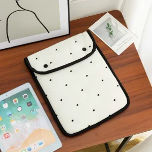 Detalle de funda acolchada blanca para tablet con lunares negros en escritorio