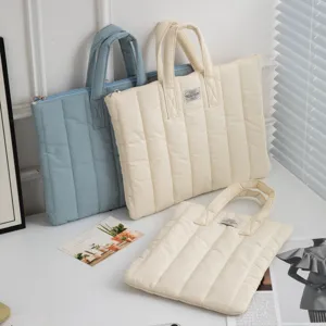Nahaufnahme von gesteppten Laptoptaschen in Beige und Blau mit weicher Textur und Griffen