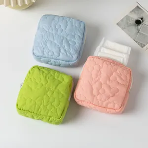 Detailed view of quilted candy-colored sanitary napkin storage pouches in three colors