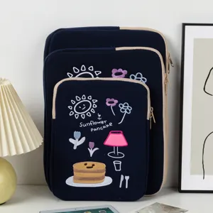 Navy blue embroidered laptop sleeve featuring sunflower and pancake motifs on desk