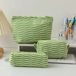 Close-up of three green and white striped knitted pouches on a white desk