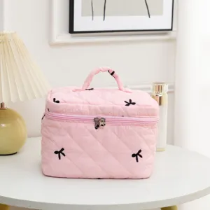Close-up of pink quilted fabric makeup bag showing black bow embroidery details