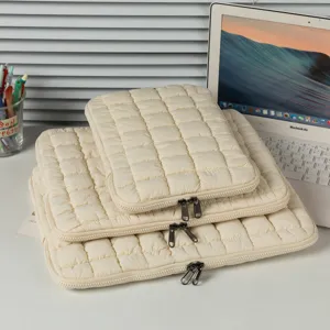 Drei gesteppte cremefarbene Laptoptaschen in verschiedenen Größen auf einem Schreibtisch.