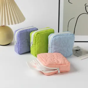 Detailed view of multiple candy-colored quilted storage pouches for sanitary napkins