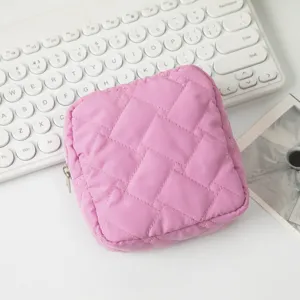 Nahaufnahme einer lila gesteppten quadratischen Kosmetiktasche auf einem weißen Tisch