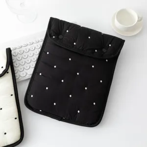 Vista detallada de la funda acolchada negra para tableta con estampado de lunares bordados