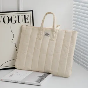 Cremefarbene gesteppte Laptoptasche in einer Lifestyle-Szene mit Magazin und Hintergrund.