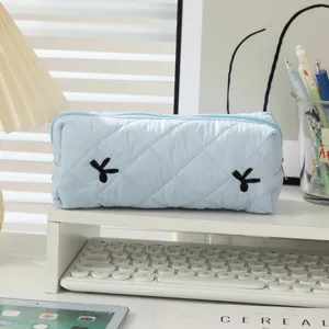 Close-up of light blue quilted pencil case on a minimalist white desk setup
