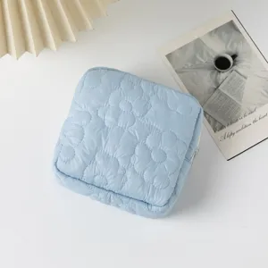 Macro detail view of a light blue quilted cosmetic bag with soft floral stitching
