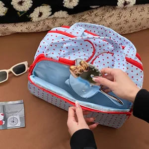 Detailansicht: Hand legt einen Spiegel in eine blaue Kulturtasche mit Herzmuster