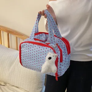 Detailansicht einer blau gesteppten Kulturtasche mit Herzmuster und Hundeanhänger