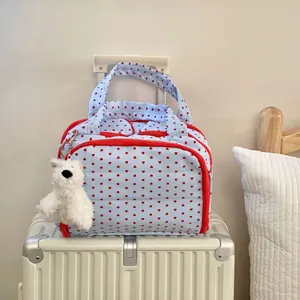 Blaue Reisetasche mit rotem Herzmuster und süßem Hundekopf-Anhänger auf dem Koffer