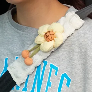 Detailansicht eines weißen gesteppten Sicherheitsgurt-Bezugs mit dekorativer gelber Blume