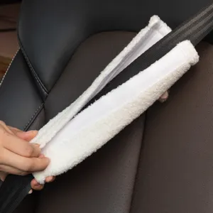 Detailansicht eines weichen weißen Plüsch-Sicherheitsgurtpolsters bei der Montage im Auto