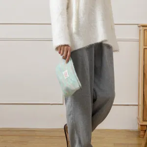 Primo piano di una borsa cosmetica arcobaleno in peluche con consistenza morbida e cerniera