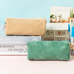 Deux trousses en velours côtelé vintage beige et vert avec des livres et des stylos