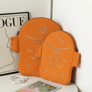 Close-up of two cute orange fish-shaped protective laptop sleeves on a white table