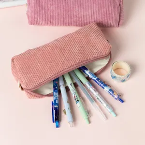 Vue détaillée d'une trousse en velours côtelé rose avec des stylos et du ruban adhésif