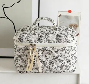 Detailansicht der gesteppten Baumwoll-Kosmetiktasche mit schwarzem Blumendruck und Bändern