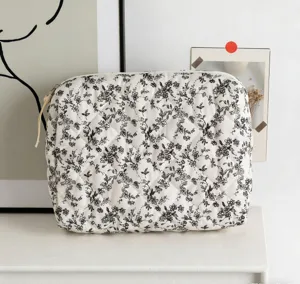 Detailaufnahme einer weiß gesteppten Baumwoll-Kosmetiktasche mit schwarzem Blumendruck