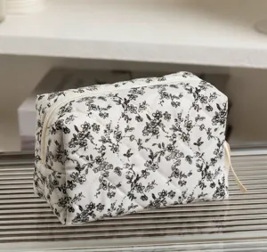 Detailansicht der weißen gesteppten Baumwoll-Kosmetiktasche mit schwarzen Blumenmustern