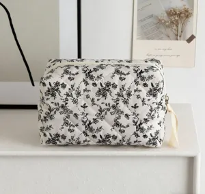 Detailansicht einer gesteppten Baumwoll-Kosmetiktasche mit schwarzem Blumenmuster