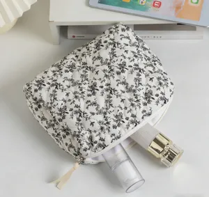 Detailansicht der gesteppten Baumwoll-Kosmetiktasche mit floralem Muster und Inhalt.