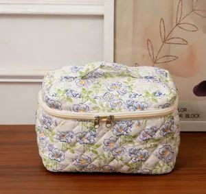 Detailed close-up of the quilted floral fabric and golden double zipper on this bag