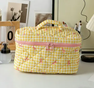 Detailansicht einer gelb karierten, gesteppten Kosmetiktasche aus Baumwolle mit rosa Schleifen