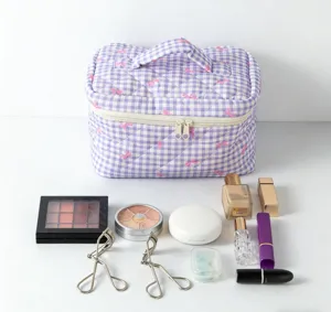 Kosmetiktasche aus Baumwolle mit Karomuster und verschiedenen Make-up-Utensilien davor