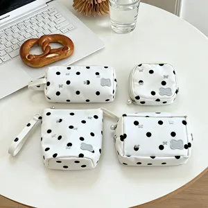 Set of four stylish white polka dot stationery pouches in various shapes on a desk